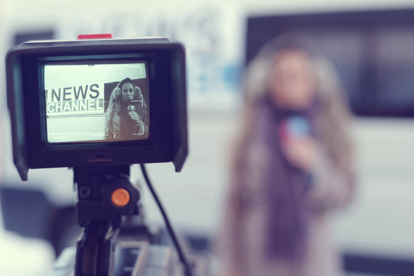 Image focused on the screen of a camera which is recording a journalist