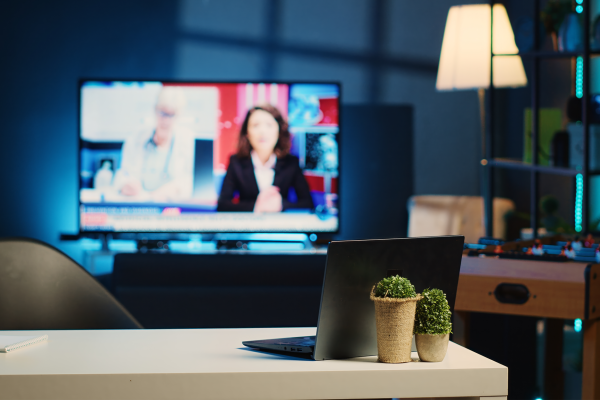 A dark living room with a TV turned on to what looks like a news channel.