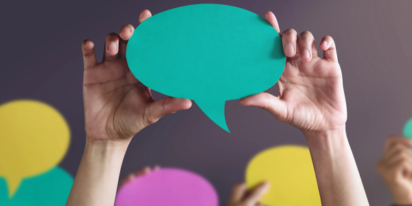 Hands holding up a construction paper speech bubble
